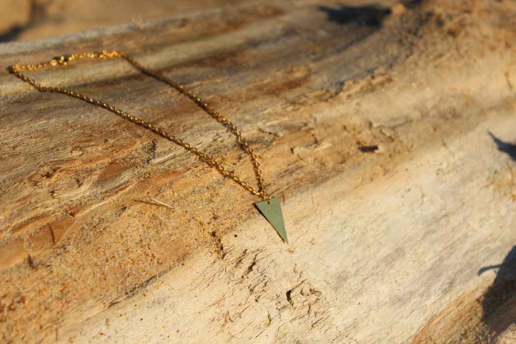 Le collier THAOPI, triangle doré, sur le bois flotté de la plage d'Hossegor.