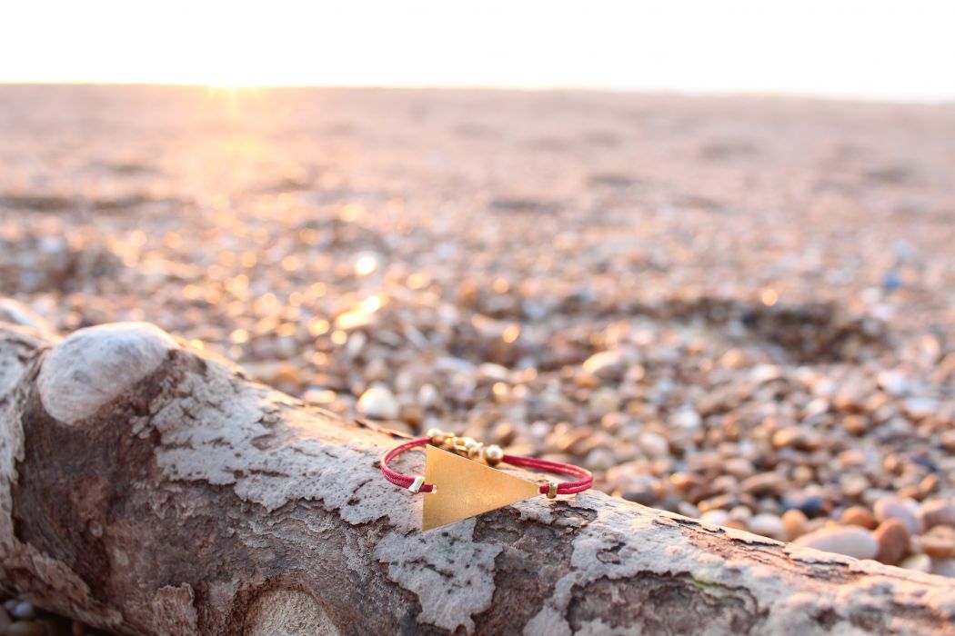 Le bracelet KANTI Bordeaux, triangle doré et fil de jade, sur la plage d'Hossegor